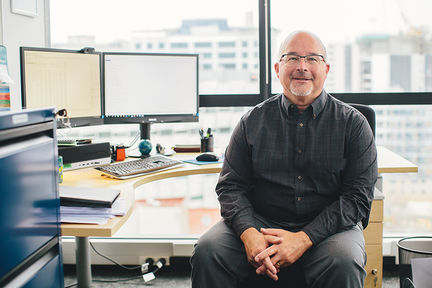 Professor Tim Maloney, smiling and sitting at his desk.