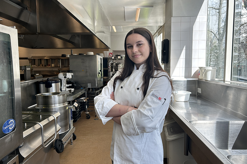 Emily Morgan in her chef whites, standing in AUT's kitchens.