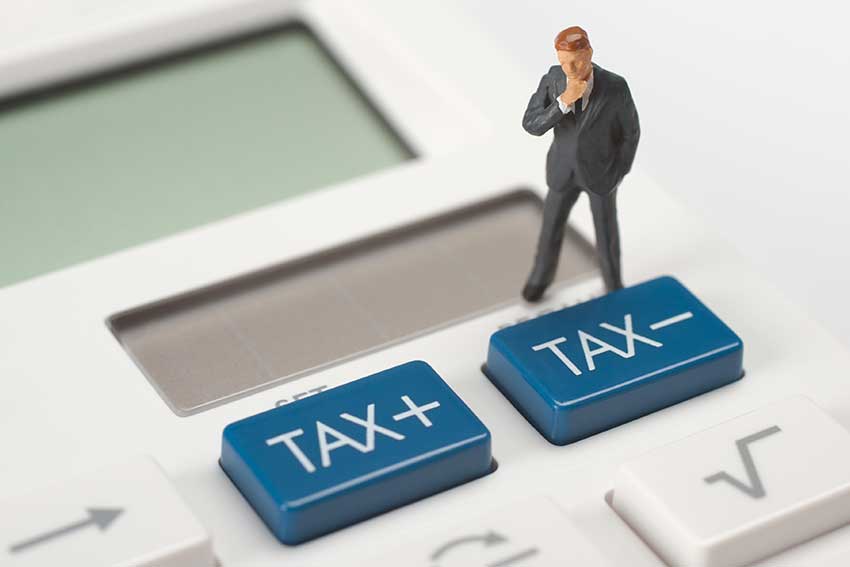 Tax concept - think figurine stand on calculator near tax buttons.