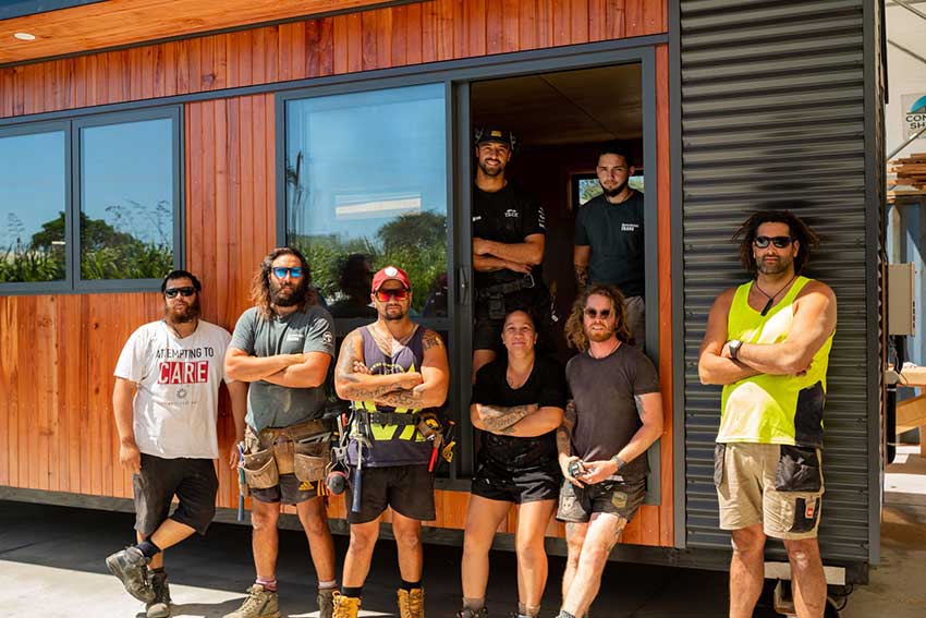 The Whare Ora team standing in front of portable house.